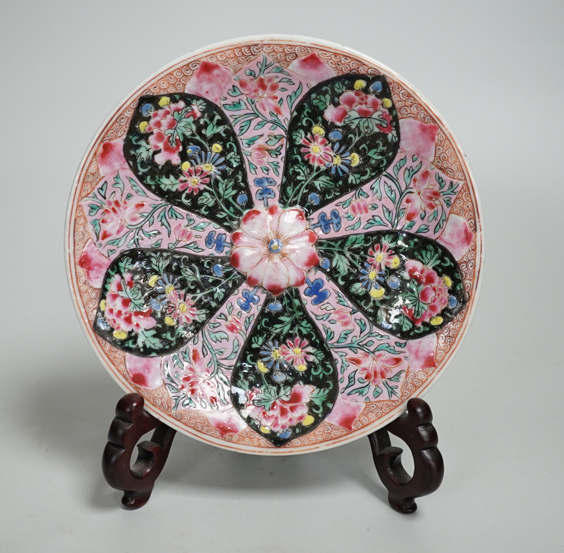A Chinese famille rose cup stand, early Qianlong period, decorated in relief with a flowerhead, 15cm in diameter